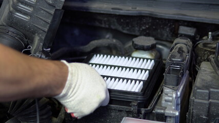 Repairman installs a new air filter in a car engine