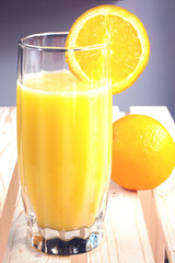 glass of cold orange juice with orange slice and whole orange