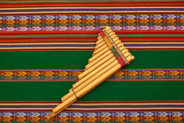 Arte textil de cultura Incaica de distintos colores y zampoña. Rojo y verde. Colores navideños. 
