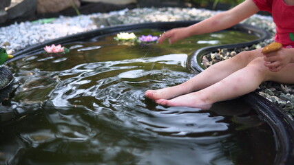 Little girl washes a mushroom. Girl watering the legs in the pond.