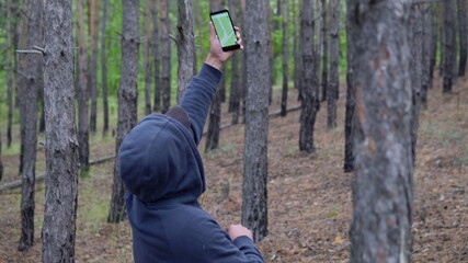 Man in a hood in the forest with a navigator in a smartphone