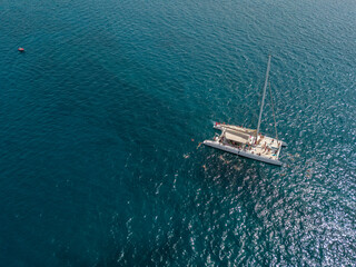 Aerial view of a catamaran with person on board and in the sea swimming, near the coasts of the island of Lanzarote, Canary, Spain. Jet ski performing in the sea
