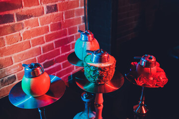 Red shisha hookah with smoke and red sparks on wood table brick, art background. Shisha Concept.