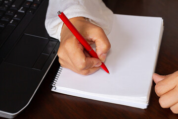 Woman working, taking notes with her notebook and red pen.
