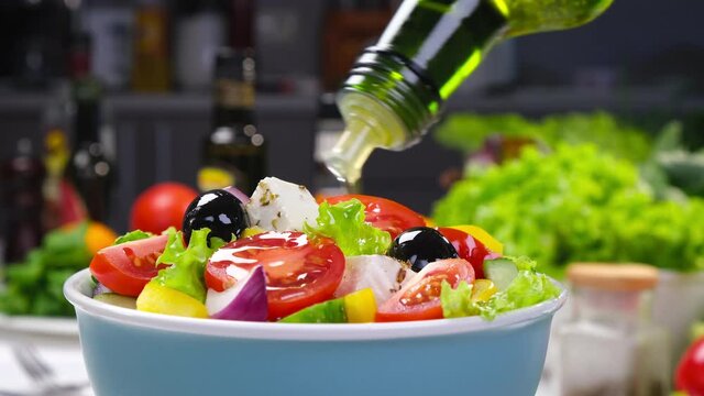 Pouring Olive oil on fresh Vegetable salad, mediterranean cuisine, Greek salad, white table served with healthy food ingredients