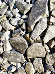 texture of large stony rubble in different shades of gray with patches of yellow, top view close to the background