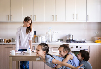 Children having fun and playing and tired mother in the messy kitchen