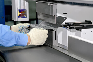 Worker bends a metal plate on the industrial machine. Process of bending a workpiece on an...