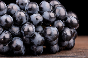 A bunch of black grapes on a wooden table.