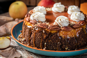 Pumpkin cheesecake. Curd cake with caramel, nuts, whipped cream, pumpkin, apples and autumn leaves on the background.