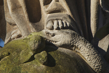 Close up Virgin Mary crushing with her foot the serpent as a symbol of the victory of good over evil. Horizontal image.