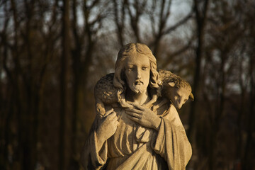 Jesus Christ Good Shepherd with the lost sheep on his shoulders. Ancient statue. Horizontal image.
