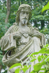 Antique stone statue of Jesus Christ pointing on his heart.