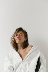 Fototapeta premium Portrait of beautiful young woman with brown hair and clean bronze skin without makeup on white background. Natural and healthy look. Neutral interior. Soft light. 