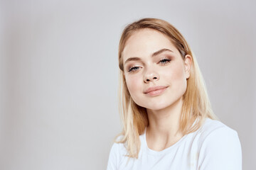 Fototapeta premium Cheerful blonde woman in white t-shirt cropped view light background
