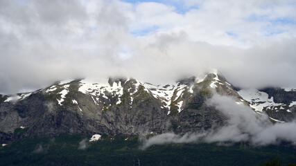 Fototapeta premium Snow covered, cloudy mountain peaks close to Voss, Norway