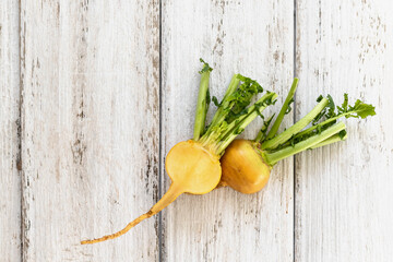 Cut yellow turnip with leaves on a white wooden background. Useful vitamins from root vegetables all year round