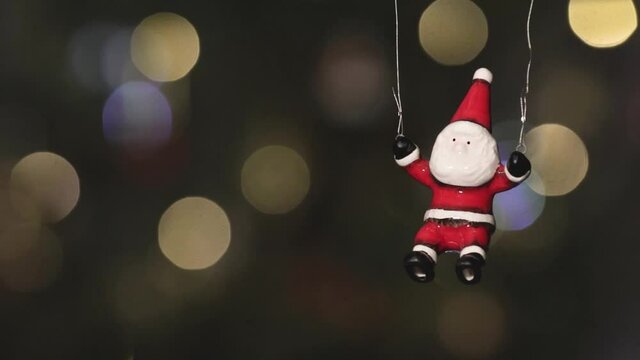 Toy Santa Claus flies against the background of twinkling colored lights of the New Year's garland. Close-up