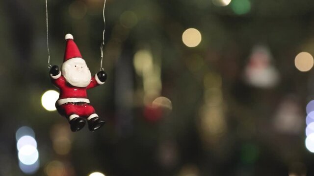 Toy Santa Claus flies against the background of twinkling colored lights of the New Year's garland. Close-up