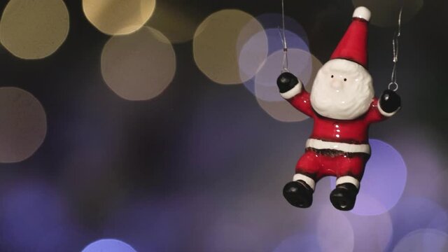 Toy Santa Claus flies against the background of twinkling colored lights of the New Year's garland. Close-up