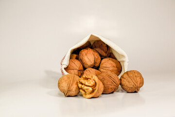 Walnuts in their shells fell out of the bag on a gray background.