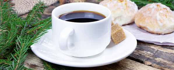 A cup of coffee and cake on a wooden background. Banner. Green fir branch on a table. Cane sugar. A cup of espresso.