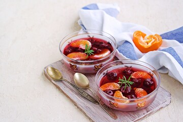 Dessert, sweet fruit jelly with cherries and tangerines in portioned bowls on a concrete background. Lenten desserts.