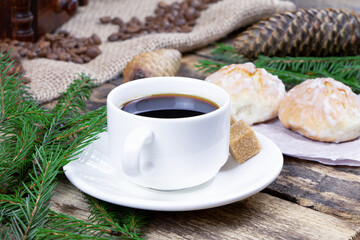 A cup of coffee and cake on a wooden background. Green fir branch on a wooden table. Cane sugar. A cup of espresso