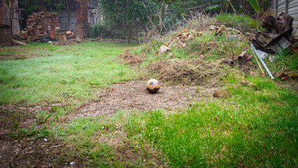 Old ruined soccer ball, abandoned in a wild meadow full of rubbish. Color image.