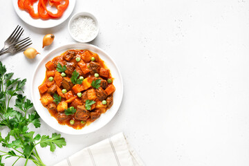 Beef stew with potatoes and carrots in tomato sauce on white plate