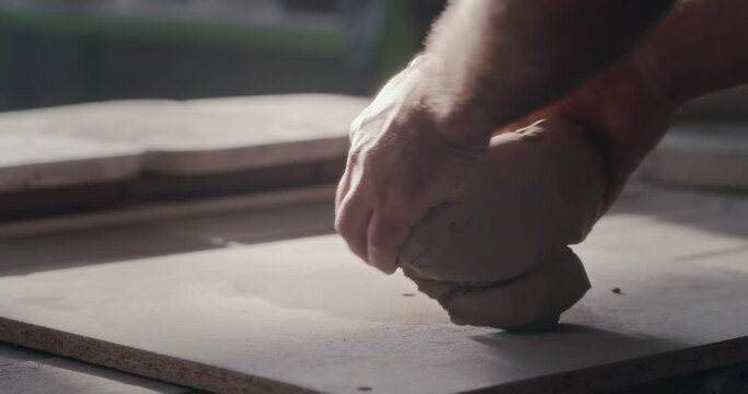 Crop potter kneading clay on workbench