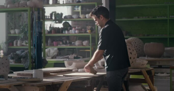 Male ceramist kneading clay in spacious studio