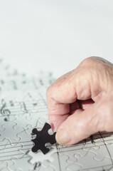 Elderly hand fits puzzle piece