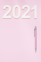 New year 2021 planning concept on the pastel pink background with a pink pencil. Minimalistic design. Copy space.