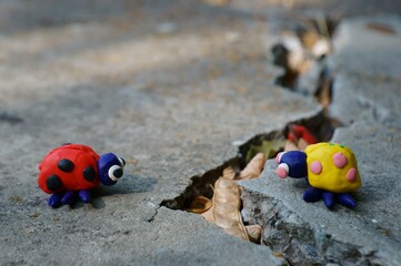 Obraz premium Figurines of two ladybirds made of plasticine. The figures are placed opposite each other. There's a crack between them.