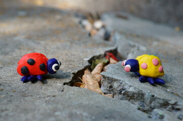 Figurines of two ladybirds made of plasticine. The figures are placed opposite each other. There's a crack between them.