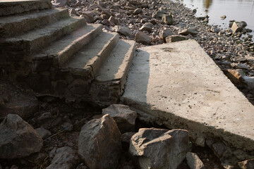 Close-up shot of the wreckage of an old cement staircase descending to the water on the embankment....