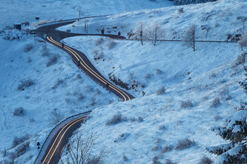 Snow covered road in the mountains with car lights