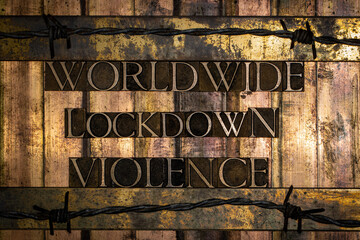 Worldwide Lockdown Violence text message on textured grunge vintage bronze bars surrounded by barbed wire