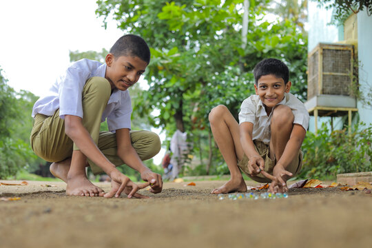 Indian child playing with glass marbles which is an old Indian village game. Glass Marbles are also called as Kancha in Hindi Language.