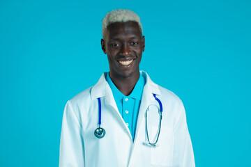 Portrait of smiling african doctor in professional medical coat . Doc man isolated on blue background.