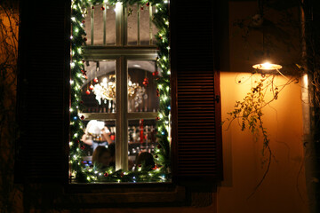 Stylish decorated windows with christmas branches, warm lights and ornaments in evening