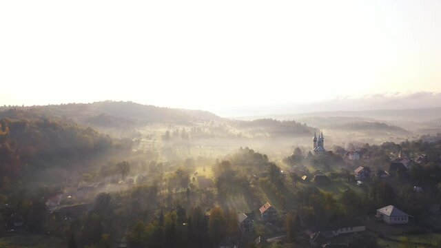 Aerial 4K footage: Flight over autumn mountain village of Breb in sunrise. Carpathian Mountains, Maramures, Romania.