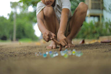 A child playing with glass marbles which is an old Indian village game. Glass Marbles are also...