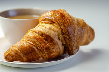 Croissant with chocolate on a plate with coffee in a cup