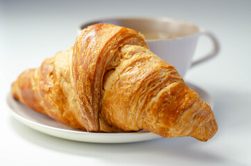 Croissant with chocolate on a plate with coffee in a cup