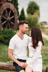 Fototapeta premium Couple in love walks near a large wooden mill on summer day. man and woman are having fun outdoors.
