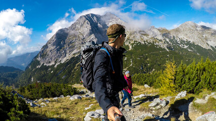 A couple hiking in Austrian Alps to the top of Hochzin?dl. High, steep mountain chain behind them....