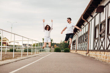 happy young man and woman jumping and having fun outdoors on a warm summer day. horse rancho