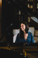 Piano teacher seated in front of a grand piano smiling